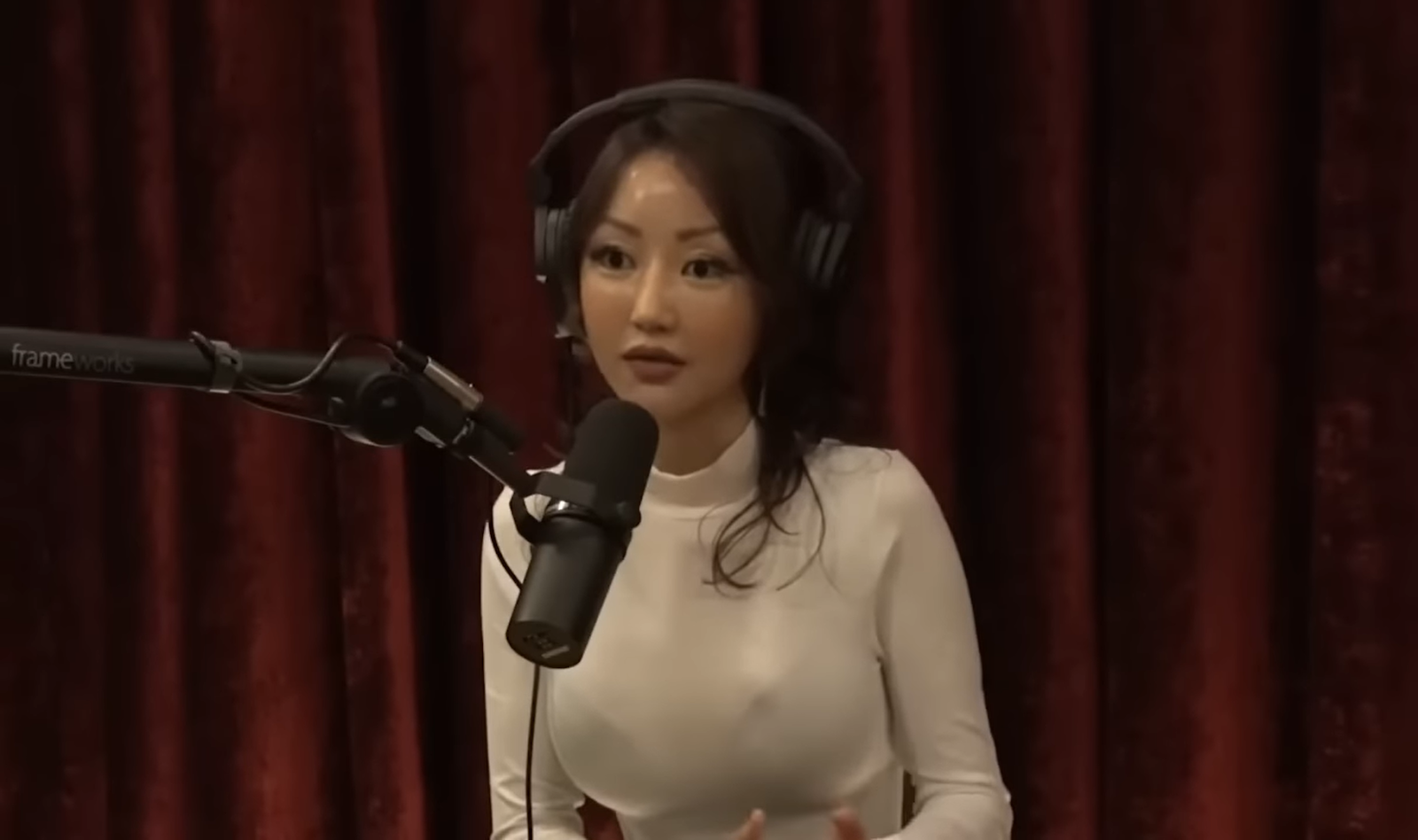 Yeonmi Park sitting in front of velour red curtains near the microphone